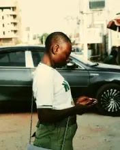 Un jeune lit un message sur son téléphone dans une rue d’Abuja.