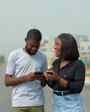 Deux amis regardent leurs téléphones dans la rue.